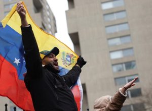 A person supporting the capture of Venezuelan President Nicolas Maduro displays a Venezuelan flag, as people protest against U.S. strikes against Venezuela and the capture of Maduro, outside the Daniel Patrick Moynihan United States Courthouse ahead of his arraignment to face U.S. federal charges including narco-terrorism, conspiracy, drug trafficking, money laundering and others in New York City, U.S., January 5, 2026. REUTERS/Shannon Stapleton